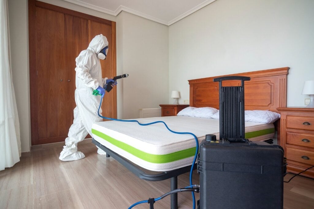 exterminator spraying a room for bed bugs